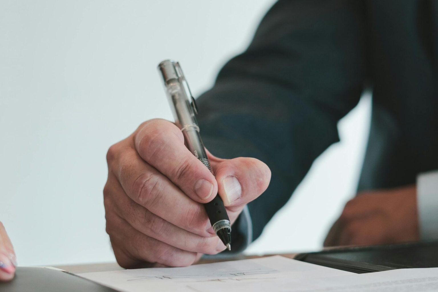 A businessman in a suit signing a contract in an office setting, emphasizing professional context.